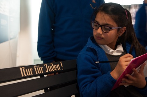 A school child sits on the replica bench marked 'Nur fur Juden' (Only for Jews) in the Holocaust Exhibition and Learning Centre.